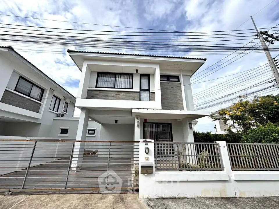 Modern two-story house with gated driveway and contemporary design.