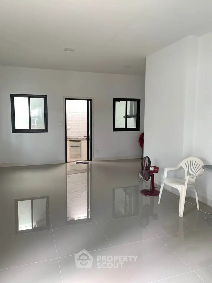 Spacious empty room with glossy tiled floors and large windows, perfect for customization.