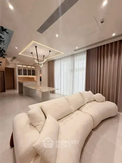Luxurious modern living room with elegant sofa and open kitchen layout.
