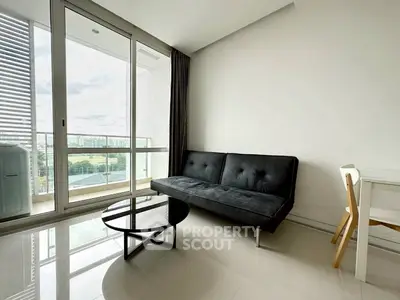 Modern living room with sleek black sofa and glass coffee table, featuring a spacious balcony with city view.