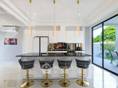 Luxurious modern kitchen with sleek island and stylish bar stools, featuring open layout and large glass doors.