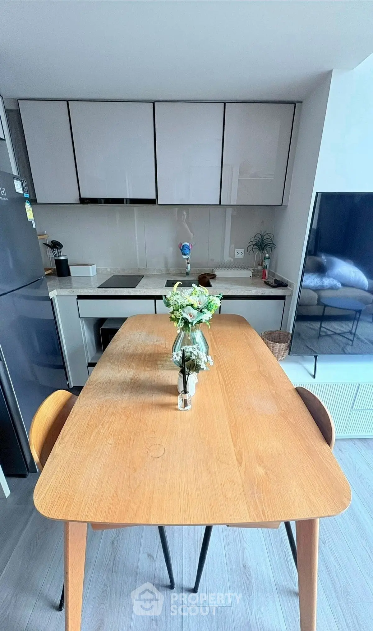 Modern kitchen with sleek cabinets and wooden dining table, perfect for cozy meals.