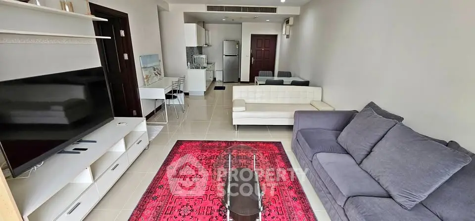 Spacious living room with modern furniture and vibrant red rug in a stylish apartment.