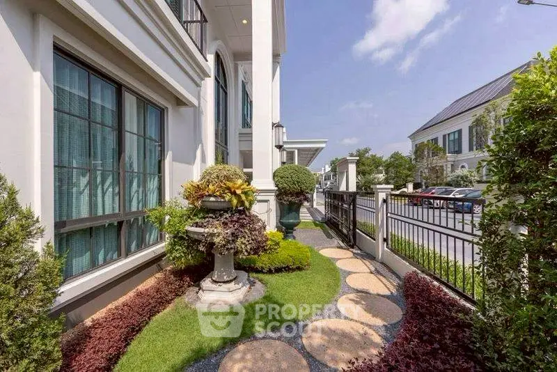 Charming garden path beside elegant residential building with lush landscaping and modern architecture.