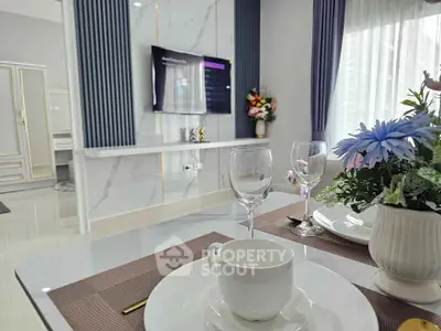 Elegant dining area with modern decor and wall-mounted TV in a stylish apartment.