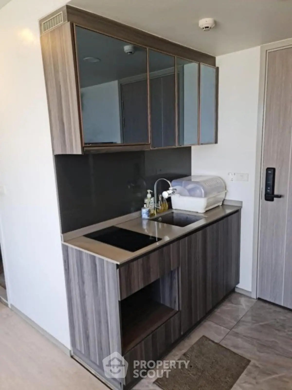 Modern compact kitchen with sleek cabinetry and induction cooktop in a stylish apartment.
