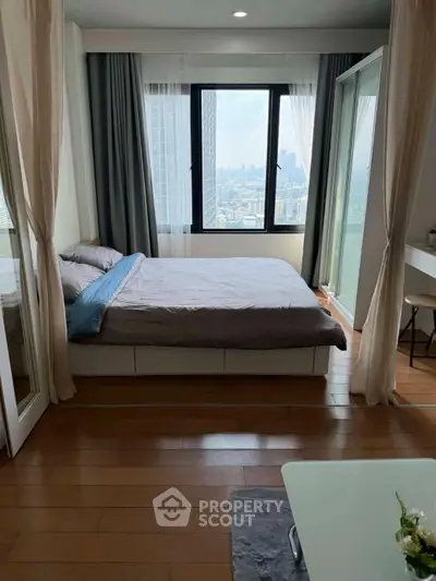Modern bedroom with city view, featuring large windows and elegant decor.