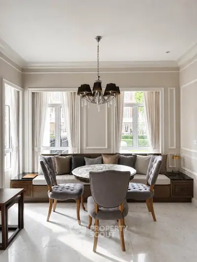 Elegant dining area with stylish chairs and chandelier in a bright, cozy room.