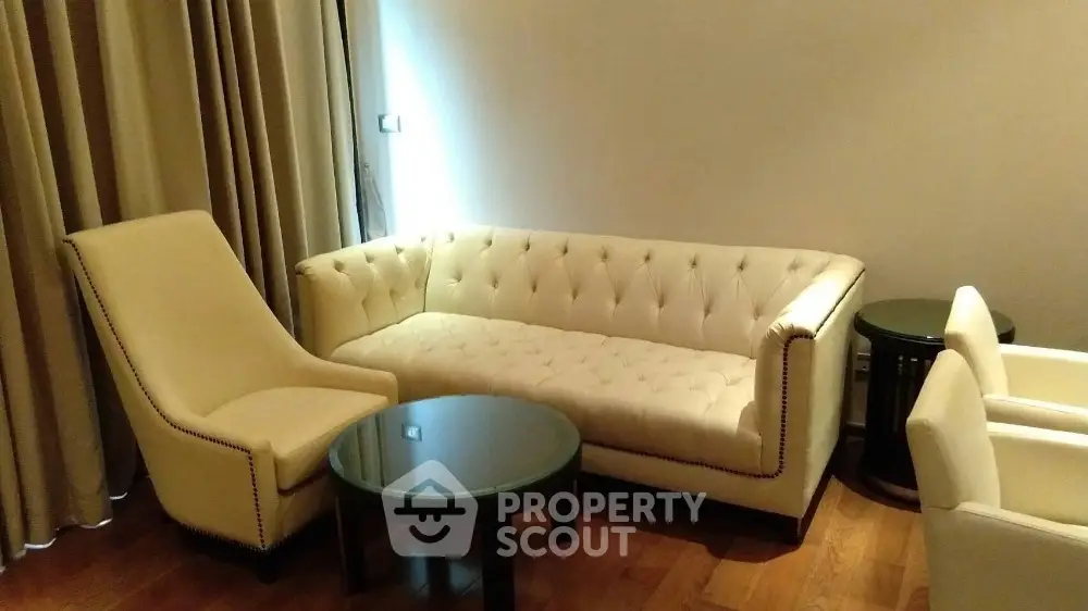 Elegant living room with plush white sofa and armchairs, complemented by a sleek round coffee table.
