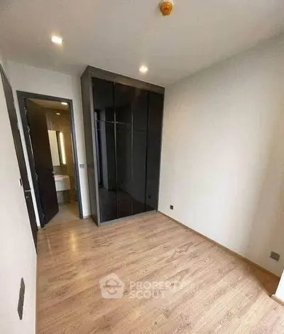 Spacious bedroom with wooden flooring and built-in wardrobe in modern apartment.