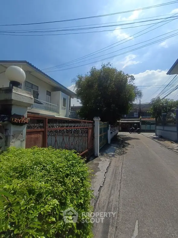 Charming residential street view with lush greenery and classic architecture.
