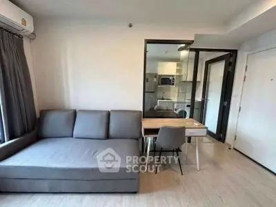 Modern living room with gray sofa and compact kitchen in open layout apartment.