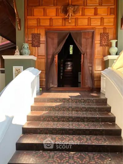 Elegant entrance with wooden paneling and decorative tiles, leading to a luxurious interior.