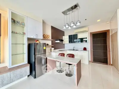 Modern kitchen with sleek design, featuring a breakfast bar, stainless steel fridge, and stylish lighting.