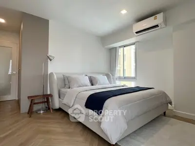 Modern bedroom with stylish decor and natural light, featuring a cozy bed and sleek flooring.