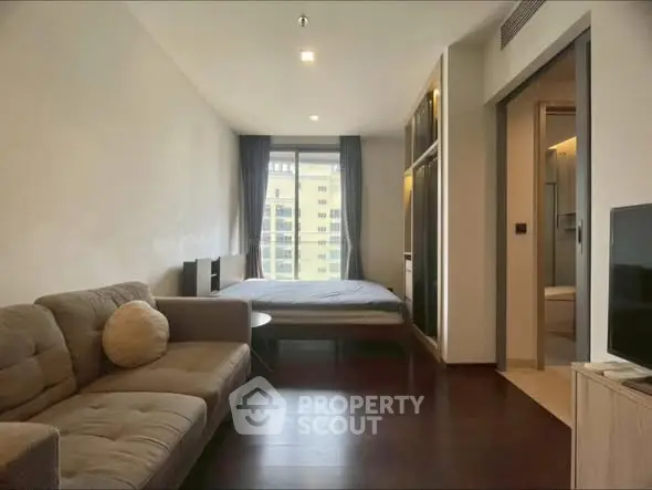 Modern studio apartment with cozy living area and bedroom, featuring large window and sleek design.