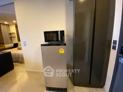 Modern apartment interior with compact kitchen appliances and cozy bedroom view.