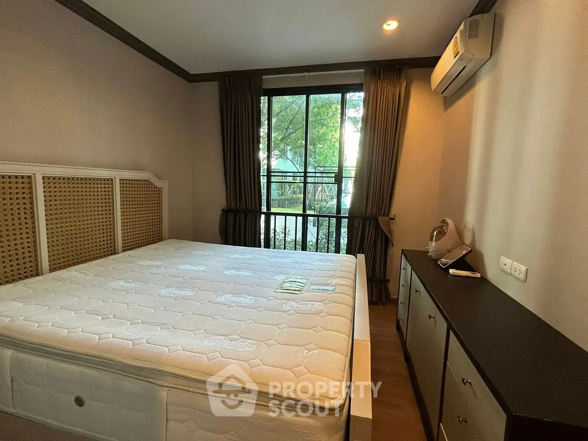Cozy bedroom with large window and air conditioning, featuring a comfortable bed and ample storage space.
