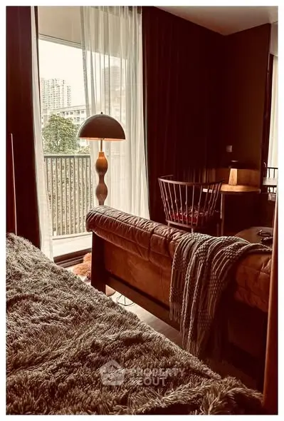 Cozy living room with plush sofa, stylish lamp, and balcony view in modern apartment.