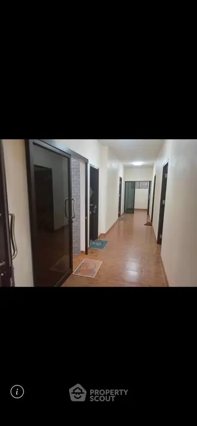 Spacious corridor with modern glass doors in a residential building, showcasing sleek design and ample lighting.