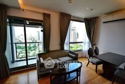 Modern living room with city view and balcony access in high-rise apartment.