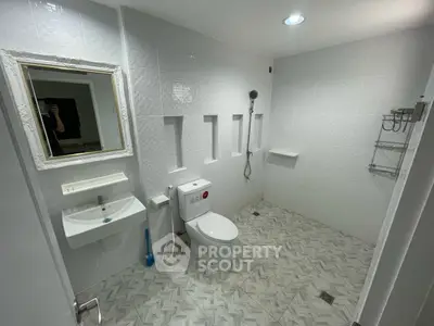 Spacious modern bathroom with elegant white tiles and sleek fixtures.