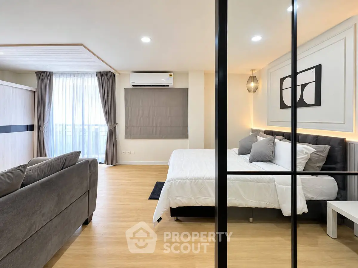 Modern bedroom with stylish decor and large window in a cozy apartment.