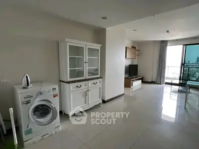 Spacious living area with modern appliances and balcony view in a stylish apartment.