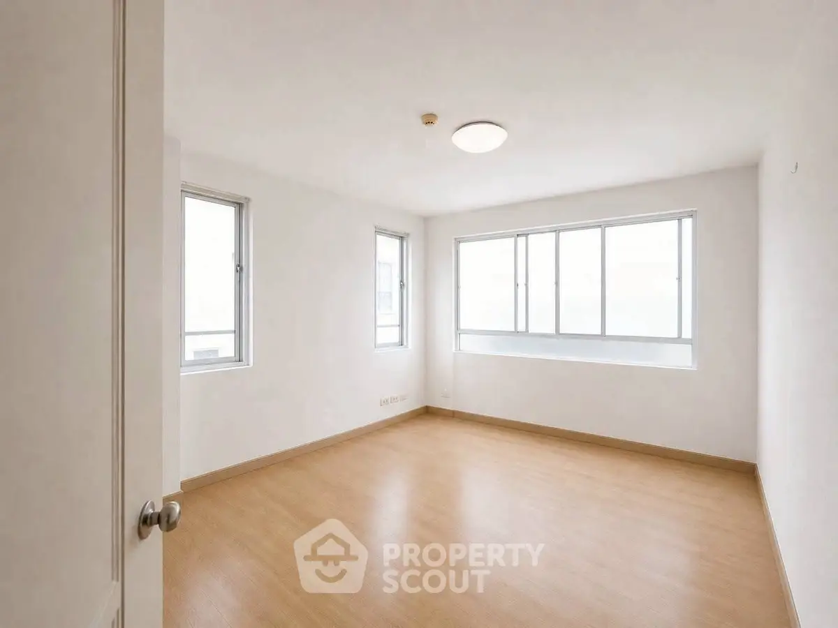 Spacious empty room with large windows and wooden flooring, perfect for customization.