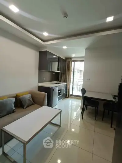 Modern open-layout living room with sleek kitchen and dining area, featuring contemporary furniture and large windows.