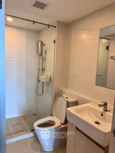 Modern bathroom with glass shower enclosure and sleek fixtures in a contemporary apartment.