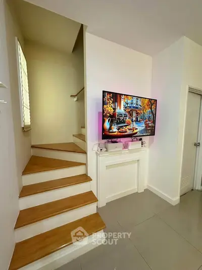Modern interior with staircase and mounted TV, showcasing sleek design and cozy ambiance.