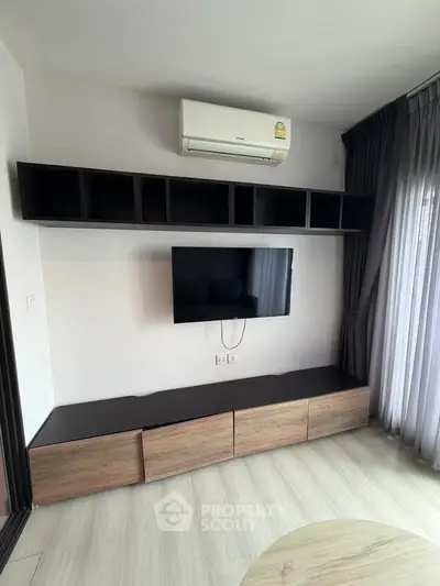 Modern living room with wall-mounted TV and sleek storage units under air conditioning.