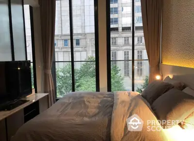 Cozy bedroom with large windows offering ample natural light and a serene city view, perfect for relaxation and comfort.