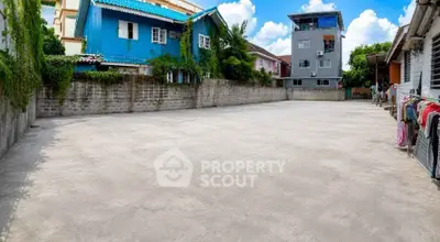 Spacious outdoor area with surrounding residential buildings, ideal for parking or recreational use.