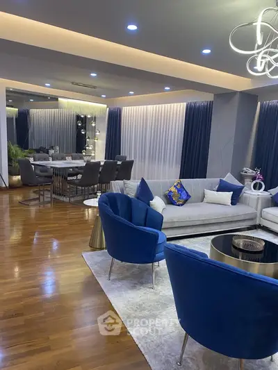 Luxurious modern living room with elegant blue accents and spacious dining area, perfect for entertaining.