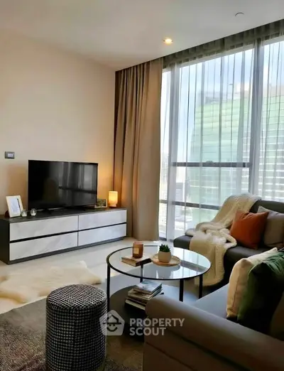 Modern living room with large windows, stylish furniture, and cozy decor in a high-rise apartment.