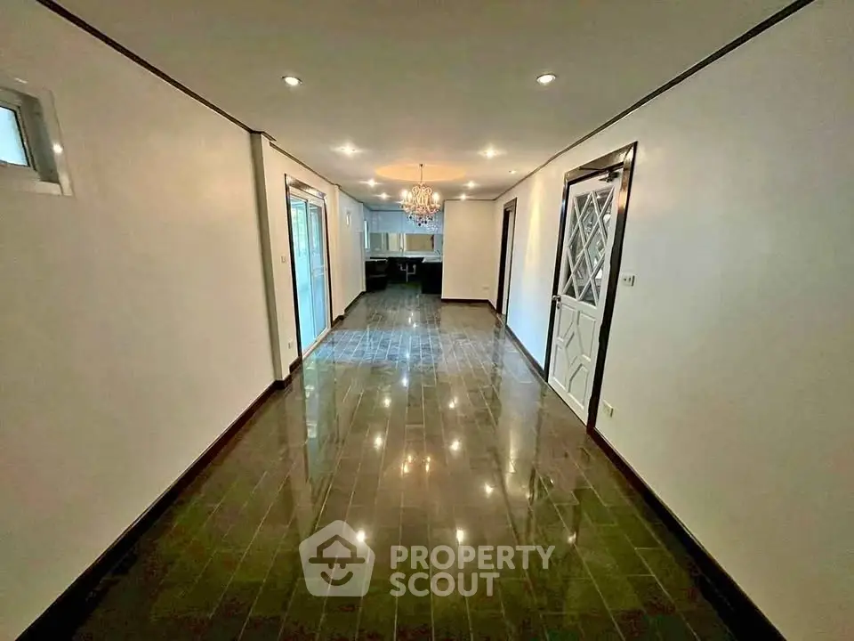 Spacious living room with glossy floors and elegant chandelier in modern home.