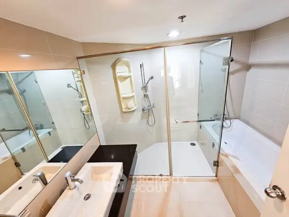 Modern bathroom with glass shower and bathtub, sleek design and neutral tones.
