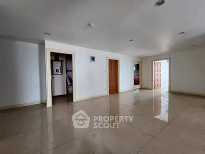 Spacious empty room with glossy tiled floors and wooden doors, ideal for customization.