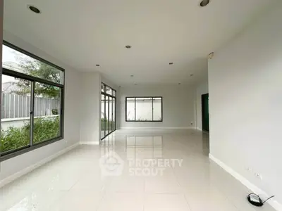 Spacious empty room with large windows and garden view, perfect for customization.