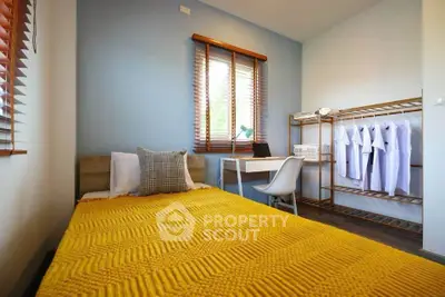 Cozy bedroom with modern decor and ample natural light, featuring a stylish workspace and organized closet.
