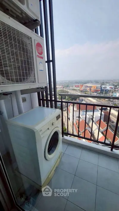 High-rise balcony with washing machine and panoramic city view, perfect for urban living.