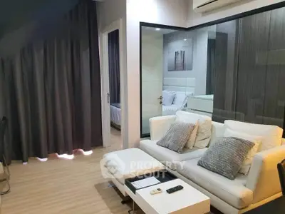 Modern living room with stylish decor and glass partition leading to bedroom.