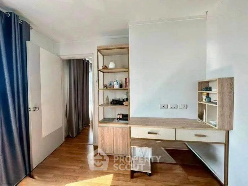 Modern study room with wooden desk and shelves, featuring natural light and elegant curtains.