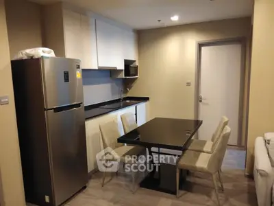 Modern kitchen with dining area featuring sleek black table and stainless steel fridge.