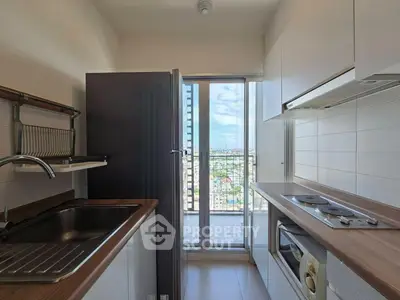 Modern kitchen with sleek appliances and balcony view in high-rise apartment