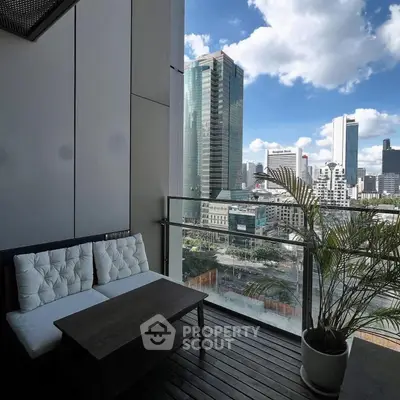 Stunning city view from a modern balcony with cozy seating and lush plant.