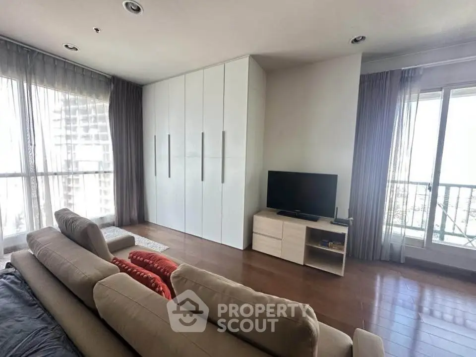 Spacious living room with modern furniture and large windows offering city views.