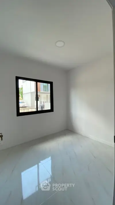 Bright empty room with large window and glossy tiled floor in modern home.
